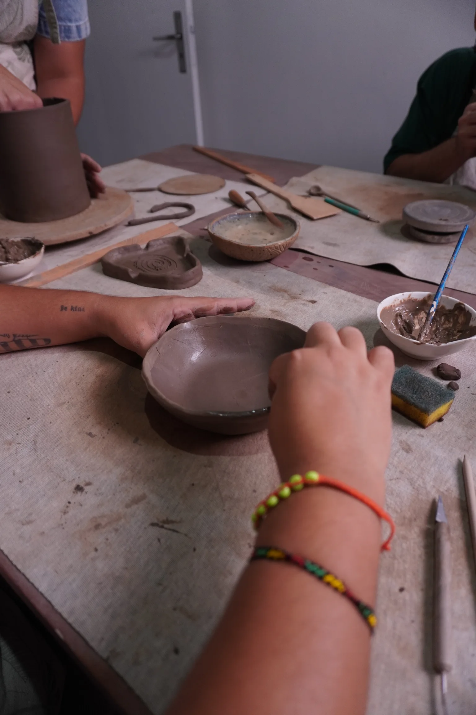Mãos trabalhando um recipiente de argila durante uma aula de cerâmica